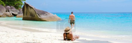 Photo for A couple of men and women sitting on the tropical white beach with turqouse colored ocean of Similan Islands Thailand. - Royalty Free Image