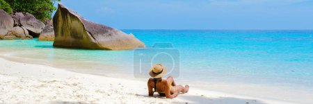 Téléchargez les photos : Femmes asiatiques allongées sur la plage de sable blanc tropical avec turqouse couleur océan des îles Similan Thaïlande. - en image libre de droit