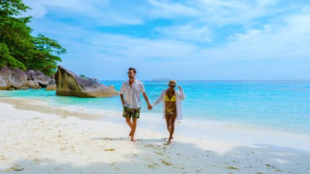 Téléchargez les photos : Un couple d'hommes et de femmes sur la plage de sable blanc tropical avec turqouse couleur océan des îles Similan Thaïlande. - en image libre de droit