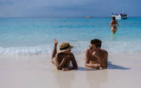 Téléchargez les photos : Des hommes et des femmes bronzer sur une plage de sable blanc, Un couple d'hommes et de femmes lors d'un voyage à l'île tropicale avec plage de sable blanc Similan Islands Thaïlande. - en image libre de droit