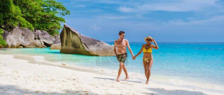 Photo for A couple of men and women walking on the tropical white beach with turqouse colored ocean of Similan Islands Thailand. - Royalty Free Image