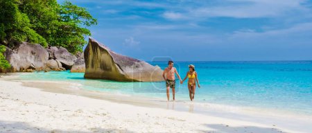 Photo for A couple of men and women walking on the tropical white beach with turqouse colored ocean of Similan Islands Thailand. - Royalty Free Image