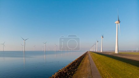 Foto de Turbinas de molino de viento en el mar con una vista del cielo azul desde una vista aérea de drones desde arriba en un enorme parque de molinos de viento en los Países Bajos. - Imagen libre de derechos