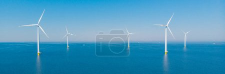 Téléchargez les photos : Turbines éoliennes en mer avec vue sur le ciel bleu depuis un drone vue aérienne d'en haut dans un immense parc éolien aux Pays-Bas. - en image libre de droit