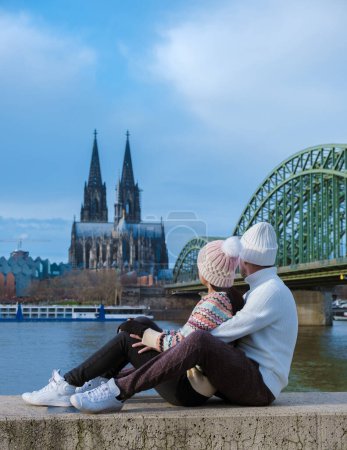 Foto de Una pareja en un viaje por la ciudad en Colonia Alemania durante el invierno en Europa sentada en el río Rin mirando al Dom de Colonia - Imagen libre de derechos