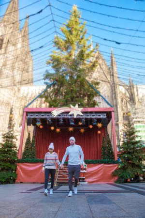Foto de Un par de hombres y mujeres visitando un mercado de Navidad en Colonia, una pareja en un viaje por la ciudad en Colonia Alemania durante el invierno en Europa. - Imagen libre de derechos