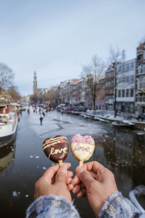 Téléchargez les photos : Voyage en ville Amsterdam pendant les Valentines avec amour romantique crème glacée et sur le fond patinage sur glace aux canaux gelés d'Amsterdam, concept romantique Valentine. - en image libre de droit