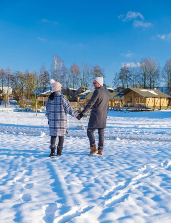 Téléchargez les photos : Un couple d'hommes et de femmes marchant dans la neige pendant une froide journée d'hiver aux Pays-Bas au parc national Sallandse Heuvelrug - en image libre de droit