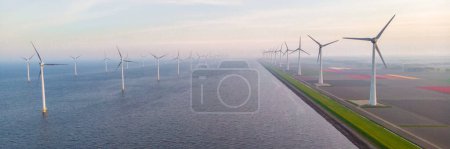 Photo for Windmill turbines at sea with a blue sky Drone aerial view at a windmill park in the Netherlands - Royalty Free Image