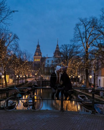 Foto de Amsterdam Países Bajos canaliza con luces de Navidad durante diciembre, una pareja en un viaje por la ciudad durante el invierno - Imagen libre de derechos