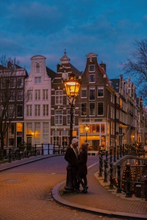 Foto de Amsterdam Países Bajos canaliza con luces de Navidad durante diciembre, una pareja en un viaje por la ciudad durante el invierno - Imagen libre de derechos