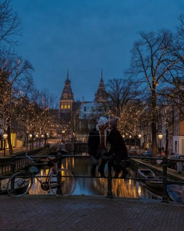 Photo for Amsterdam Netherlands canals with Christmas lights during December, a couple on a city trip during winter - Royalty Free Image