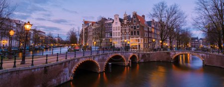 Photo for Amsterdam Netherlands canals during sunset with lights in the evening in December during wintertime in the Netherlands Amsterdam city. Europe. - Royalty Free Image