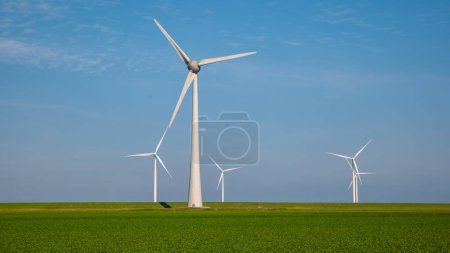 Photo for Windmill turbines with a green field with crops and a blue sky green energy concept - Royalty Free Image