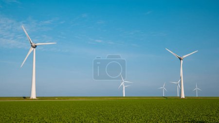Téléchargez les photos : Éoliennes avec un champ vert avec des cultures et un concept d'énergie verte ciel bleu - en image libre de droit