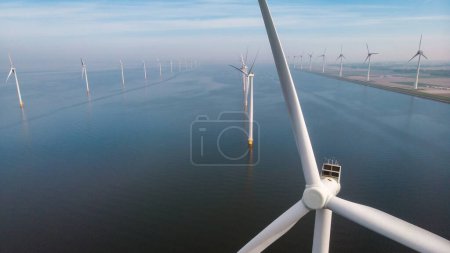 Photo for Windmill turbines at sea with a blue sky green energy concept, drone aerial view at windmill park - Royalty Free Image