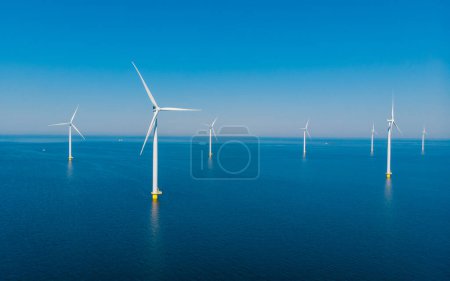Foto de Turbinas de molino de viento en vista al mar desde una vista aérea de drones desde arriba en un enorme parque de molinos de viento con un océano azul - Imagen libre de derechos