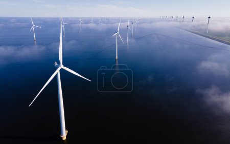 Foto de Turbinas de molinos de viento en el mar con un cielo azul y nubes vistas desde un dron - Imagen libre de derechos