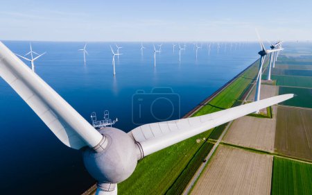 Photo for Windmill turbines at sea with a blue sky and clouds seen from a drone - Royalty Free Image