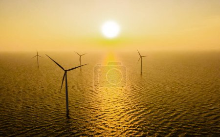 Foto de Vista aérea en el parque de molinos de viento durante la puesta del sol con turbinas de molinos de viento - Imagen libre de derechos