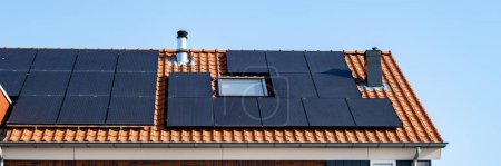 Foto de Casas de nueva construcción con paneles solares unidos al techo contra un cielo azul soleado en los Países Bajos - Imagen libre de derechos