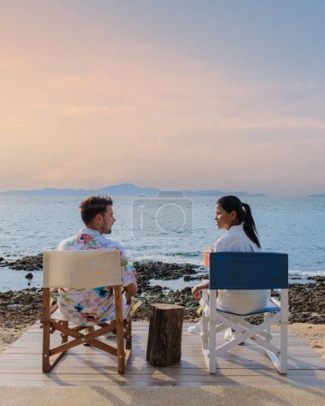 Téléchargez les photos : Couple déjeuner dans un restaurant donnant sur l'océan de Pattaya Thaïlande, homme et femme dîner dans un restaurant au bord de l'océan à Pattaya pendant le coucher du soleil - en image libre de droit