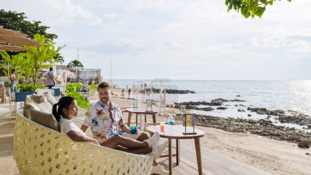 Téléchargez les photos : Couple déjeuner dans un restaurant donnant sur l'océan de Pattaya Thaïlande, homme et femme dîner dans un restaurant au bord de l'océan à Pattaya pendant le coucher du soleil - en image libre de droit
