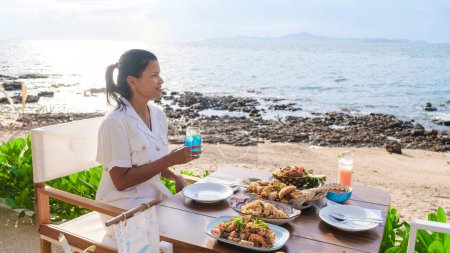Téléchargez les photos : Femmes déjeunant dans un restaurant surplombant l'océan de Pattaya Thaïlande, femmes dînant dans un restaurant au bord de l'océan à Pattaya. - en image libre de droit