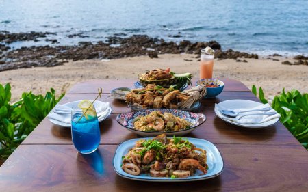 Photo for Dinner table with Thai food and bbq fish on the beach of Pattaya Thailand. - Royalty Free Image