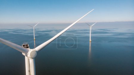 Foto de Turbinas de molinos de viento en el mar con un concepto de energía verde cielo azul enorme parque de molinos de viento en los Países Bajos - Imagen libre de derechos