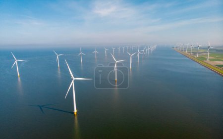Photo for Windmill turbines at sea generating electric with a blue sky green energy concept. Drone aerial view at windmill park - Royalty Free Image