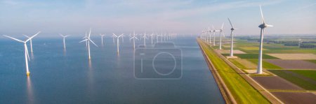 Photo for Drone aerial view at Windmill in the ocean turbines generating electricity with a blue sky green energy concept - Royalty Free Image
