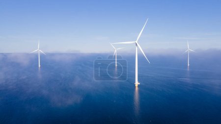 Foto de Vista aérea en el parque de molinos de viento con turbinas de molinos de viento durante el invierno generando electricidad con un concepto de energía verde cielo azul - Imagen libre de derechos
