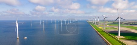 Téléchargez les photos : Vue aérienne du parc éolien avec des éoliennes pendant l'hiver générant de l'électricité avec un concept d'énergie verte à ciel bleu - en image libre de droit