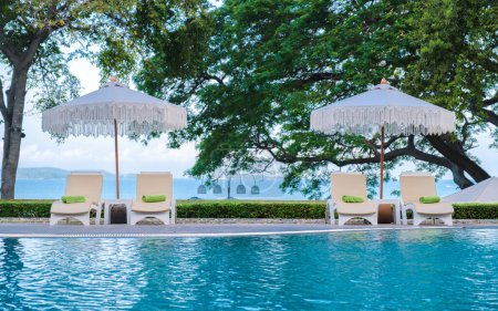 Téléchargez les photos : Chaises longues dans une piscine avec parasols, chaise longue dans une piscine le matin - en image libre de droit