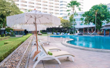 Téléchargez les photos : Pattaya Thaïlande Décembre 2022, chaises longues à une piscine avec parasols à l'hôtel de plage Cozy Pattaya - en image libre de droit