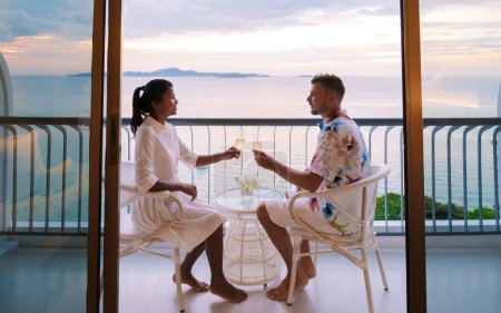 Téléchargez les photos : Quelques hommes et femmes qui boivent des cocktails sur le balcon d'un hôtel à Pattaya Thaïlande au coucher du soleil. - en image libre de droit