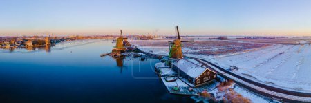Photo for Zaanse Schans windmill village during winter with snow landscape in the Netherlands Holland village in winter. Wooden historical windmills - Royalty Free Image