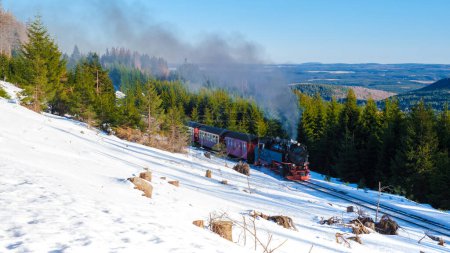Photo for Steam train during winter in the snow froest in the Harz national park Germany, Steam train Brocken Bahn on the way through the winter landscape, Brocken, Harz Germany - Royalty Free Image