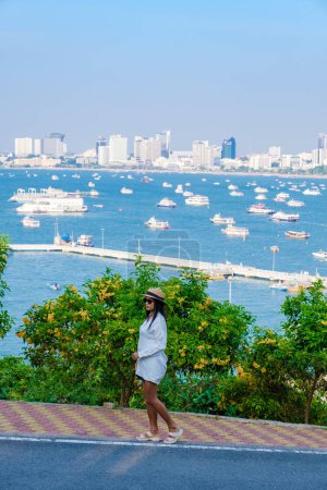 Photo for Asian Thai women at a view point looking out over the city of Pattaya skyline from the hill viewpoint Pattaya Thailand. - Royalty Free Image