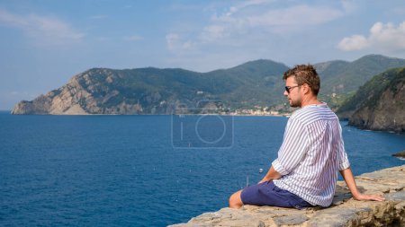 Téléchargez les photos : Jeunes hommes caucasiens visitant Riomaggiore Cinque Terre. Vue magnifique sur la Ligurie, l'Italie et l'Europe. paysage marin de la mer Méditerranée. Voyager concept arrière-plan vacances d'été - en image libre de droit