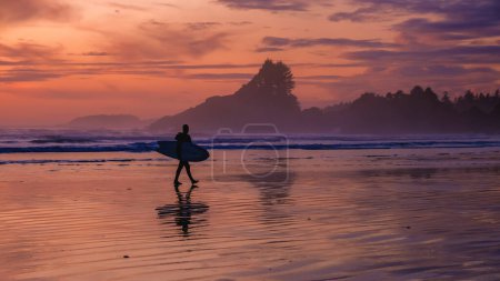Téléchargez les photos : Tofino Vancouver Island Pacific rim coast, surfeurs avec planche de surf au coucher du soleil à la plage, surfeurs silhouette Canada Vancouver Island Tofino Vancouver Island - en image libre de droit