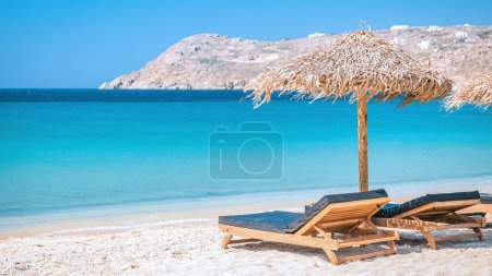 Téléchargez les photos : Mykonos plage en été avec parasol et chaises longues de luxe lits, océan bleu avec une montagne à la plage Elia Mikonos Grèce plage - en image libre de droit