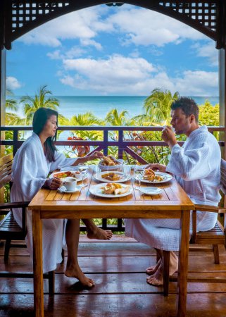 Foto de Caribe de Santa Lucía, pareja de vacaciones en la isla tropical de Santa Lucía, hombres y mujeres desayunando en el balcón con vistas al océano de Santa Lucía - Imagen libre de derechos