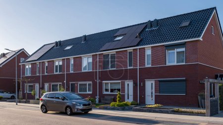 Téléchargez les photos : Maisons nouvellement construites avec des panneaux solaires fixés sur le toit contre un ciel ensoleillé Gros plan du nouveau bâtiment avec des panneaux solaires noirs - en image libre de droit