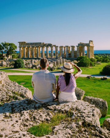 Téléchargez les photos : Un couple visite les temples grecs à Selinunte pendant les vacances, Vue sur la mer et les ruines des colonnes grecques dans le parc archéologique de Selinunte Sicile Italie - en image libre de droit