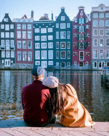 Photo for Amsterdam Damrak during sunset, happy couple man and woman on a winter evening at the canals Amsterdam at winter - Royalty Free Image