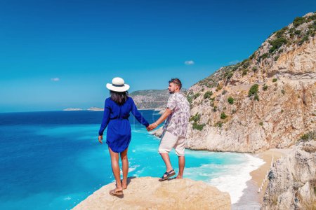 Téléchargez les photos : Couple en vacances Turquie, Kaputas Beach Kas dinde, plage blanche orange des falaises par l'océan de Kas Turquie rivera pendant l'été, les hommes et les femmes debout sur la falaise regardant l'océan pendant les vacances d'été - en image libre de droit