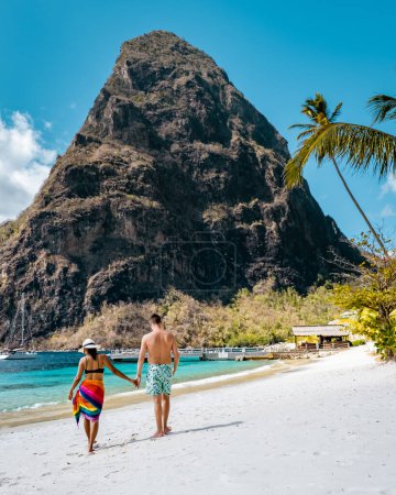 Foto de Santa Lucía, pareja caminando en la playa durante las vacaciones de verano en un día soleado en la playa de Sugar, hombres y mujeres de vacaciones en la isla tropical de Santa Lucía Caribbean Island con vistas a los Pitons - Imagen libre de derechos