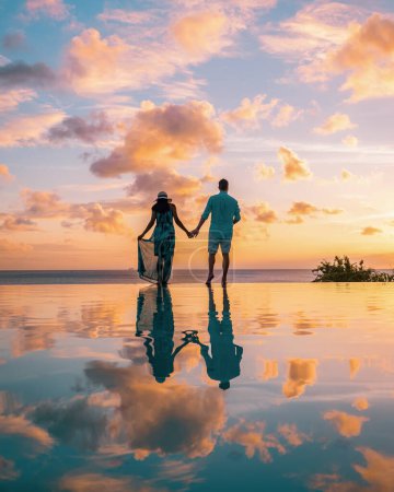 Photo for Couple watching sunset at infinity pool Saint Lucia, couple on vacation tropical Island of St Lucia with beautiful reflection in pool - Royalty Free Image